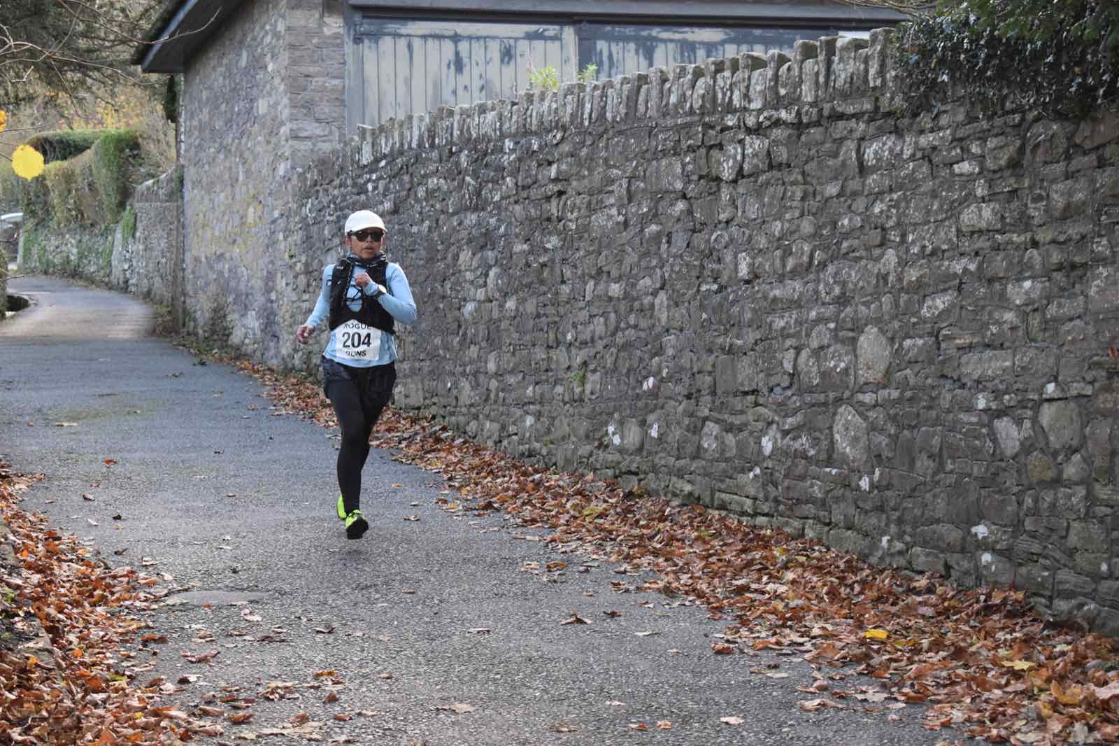 A runner approaching the finish along a stone-walled lane