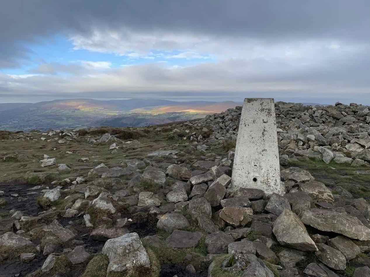 The Blorenge trig point beneath a broad cloudy sky